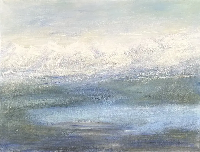 A lake below snowy mountains, in the mist